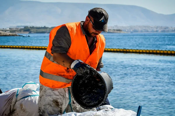 Workers try to clean up oil that has washed ashore, on a beach o — Stock Photo, Image