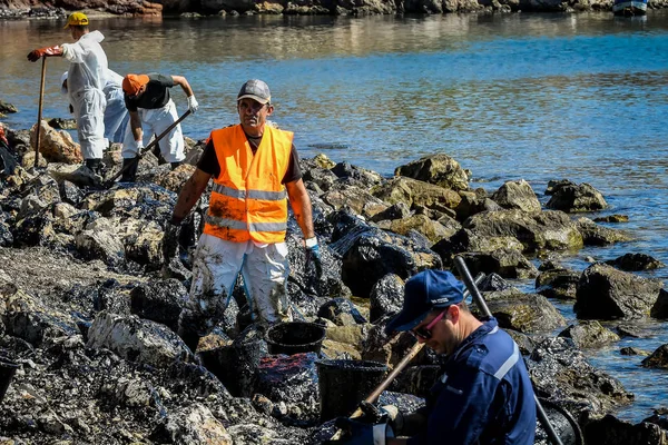 Рабочие пытаются очистить нефть, выброшенную на берег, на пляж о — стоковое фото