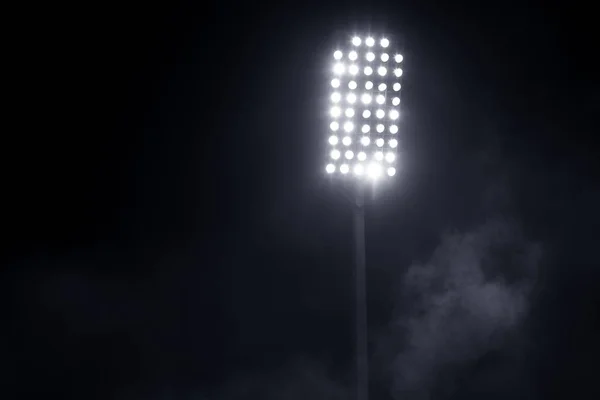 Lumières du stade et fumée sur fond de ciel nocturne sombre — Photo