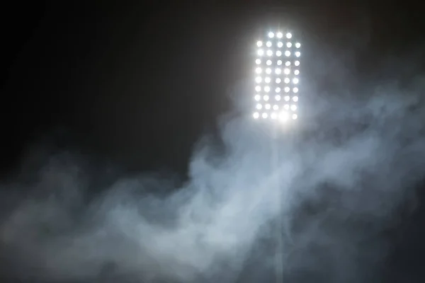 Lumières du stade et fumée sur fond de ciel nocturne sombre — Photo