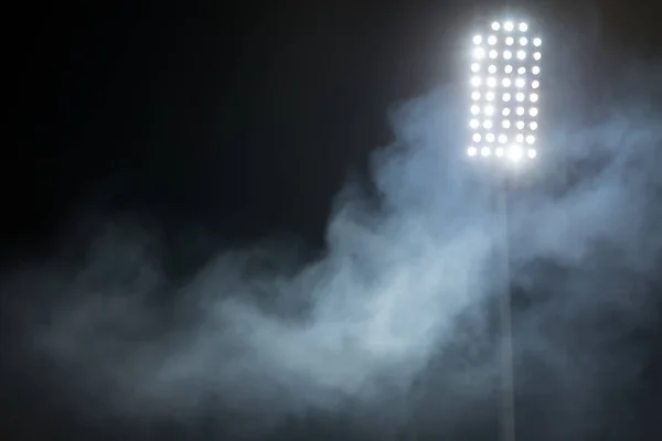 Lumières du stade et fumée sur fond de ciel nocturne sombre — Photo