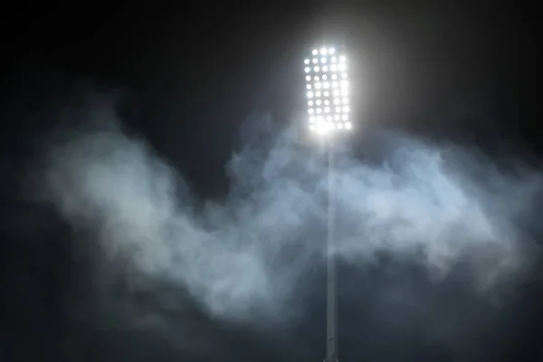 Luzes do estádio e fumaça contra fundo escuro céu noturno — Fotografia de Stock