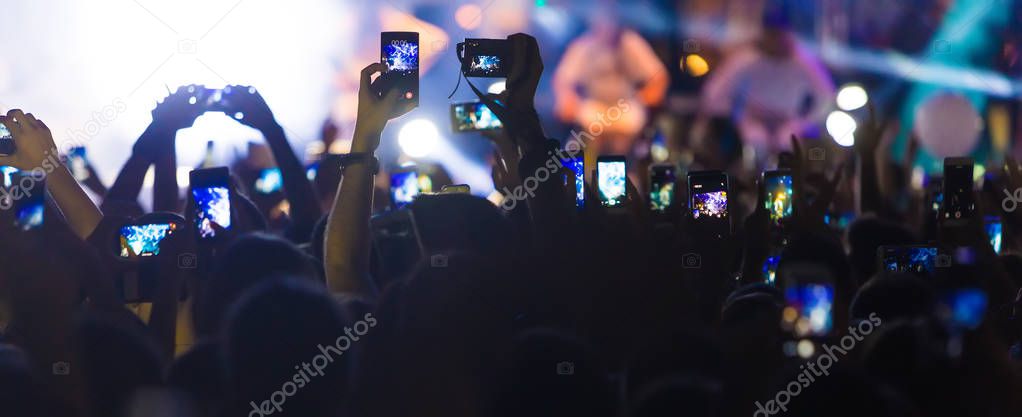 Hand with a smartphone records live music festival