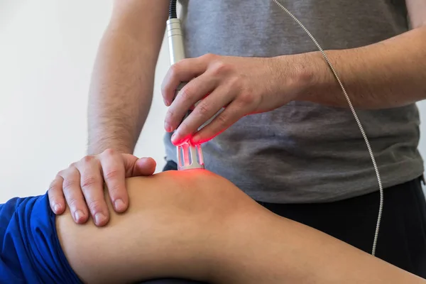 Terapia laser em um joelho usado para tratar a dor. foco seletivo — Fotografia de Stock
