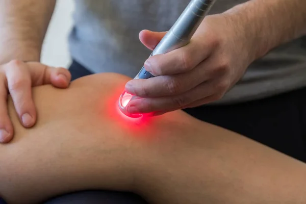 Laser therapy on a knee used to treat pain. selective focus — Stock Photo, Image