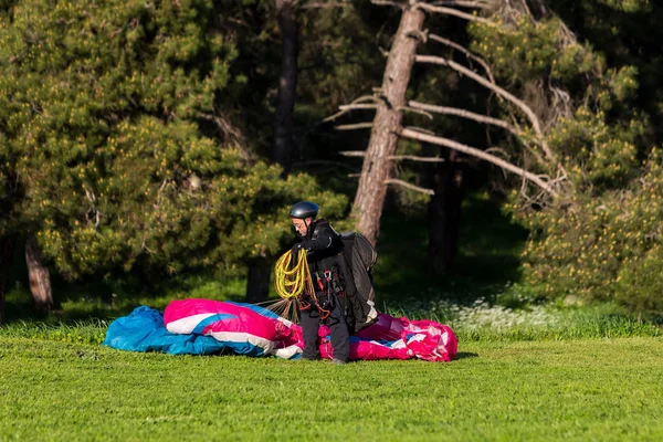 Hombre con un parapente en un campo verde después de aterrizar saludando — Foto de Stock