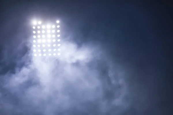 Světla na stadionu a kouř proti temné noční obloze — Stock fotografie