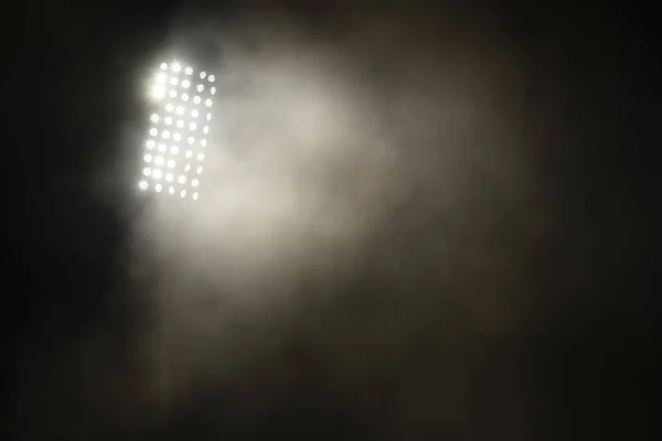 Luzes do estádio e fumaça contra fundo escuro céu noturno — Fotografia de Stock
