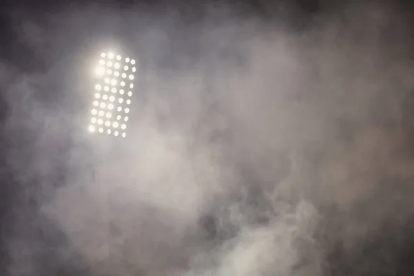 stadium lights and smoke against dark night sky background