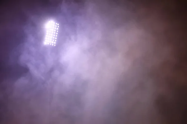 Luzes do estádio e fumaça contra fundo escuro céu noturno — Fotografia de Stock