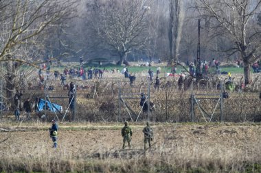 Kastanies, Evros, Greece - March 2, 2020: Greek police and soldiers in front of a fence trying to deter migrants as they attempt to enter Greece from Turkey at the Greek-Turkish border in Kastanies