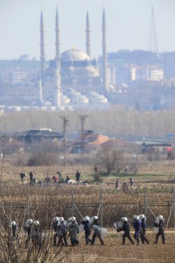 Kastanies, Evros, Greece - March 2, 2020: Greek police and soldiers in front of a fence trying to deter migrants as they attempt to enter Greece from Turkey at the Greek-Turkish border in Kastanies