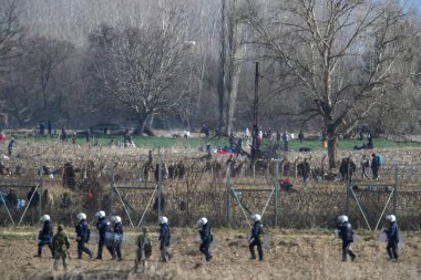 Kastanies, Evros, Greece - March 2, 2020: Greek police and soldiers in front of a fence trying to deter migrants as they attempt to enter Greece from Turkey at the Greek-Turkish border in Kastanies