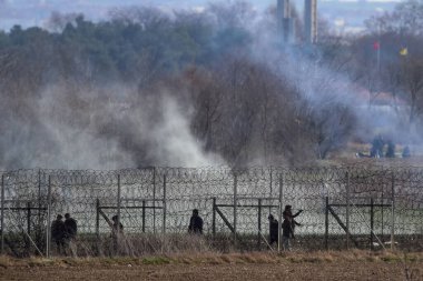 Kastanies, Evros, Greece - March 2, 2020: Greek police and soldiers in front of a fence trying to deter migrants as they attempt to enter Greece from Turkey at the Greek-Turkish border in Kastanies