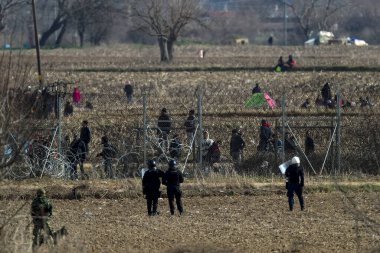 Kastanies, Evros, Greece - March 2, 2020: Greek police and soldiers in front of a fence trying to deter migrants as they attempt to enter Greece from Turkey at the Greek-Turkish border in Kastanies