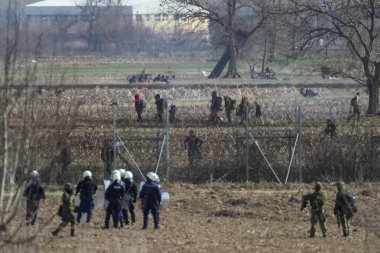 Kastanies, Evros, Greece - March 2, 2020: Greek police and soldiers in front of a fence trying to deter migrants as they attempt to enter Greece from Turkey at the Greek-Turkish border in Kastanies