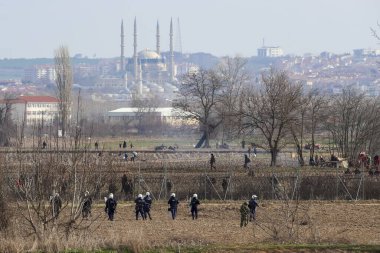 Kastanies, Evros, Greece - March 2, 2020: Greek police and soldiers in front of a fence trying to deter migrants as they attempt to enter Greece from Turkey at the Greek-Turkish border in Kastanies