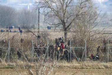 Kastanies, Evros, Greece - March 2, 2020: Greek police and soldiers in front of a fence trying to deter migrants as they attempt to enter Greece from Turkey at the Greek-Turkish border in Kastanies