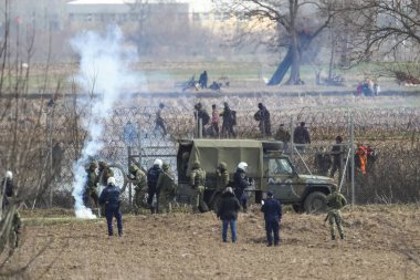 Kastanies, Evros, Greece - March 2, 2020: Greek police and soldiers in front of a fence trying to deter migrants as they attempt to enter Greece from Turkey at the Greek-Turkish border in Kastanies