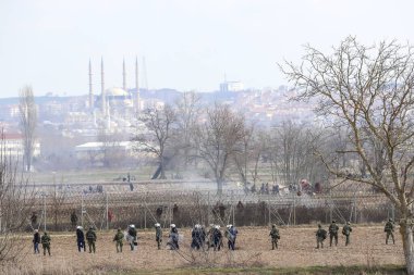 Kastanies, Evros, Greece - March 2, 2020: Greek police and soldiers in front of a fence trying to deter migrants as they attempt to enter Greece from Turkey at the Greek-Turkish border in Kastanies