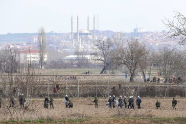 Kastanies, Evros, Greece - March 2, 2020: Greek police and soldiers in front of a fence trying to deter migrants as they attempt to enter Greece from Turkey at the Greek-Turkish border in Kastanies