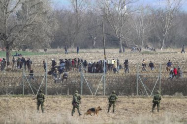 Kastanies, Evros, Greece - March 2, 2020: Greek police and soldiers in front of a fence trying to deter migrants as they attempt to enter Greece from Turkey at the Greek-Turkish border in Kastanies