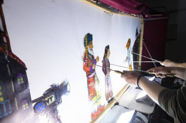 Thessaloniki, Greece - March 9, 2020: unidentified performers playing with the main character (Karagiozis) in the Greek shadow theatre behind the cotton screen during folk show.