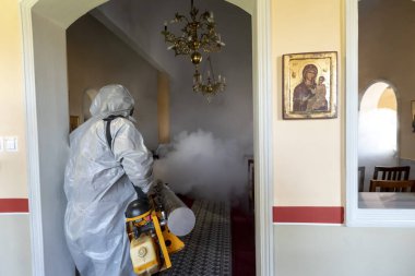 Selanik, Yunanistan - 12 Mart 2020: İşçiler, koronavirüsün (Covid-19) yayılmasını önleyici tedbirler kapsamında bir kilisede Coronavirus adlı romanı dezenfekte ediyorlar.