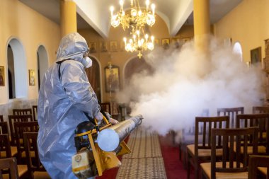 Selanik, Yunanistan - 12 Mart 2020: İşçiler, koronavirüsün (Covid-19) yayılmasını önleyici tedbirler kapsamında bir kilisede Coronavirus adlı romanı dezenfekte ediyorlar.