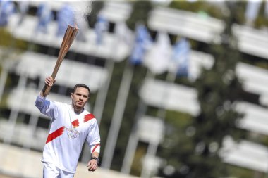 Atina, Yunanistan - 19 Mart 2020: Tokyo 2020 Yaz Olimpiyatları için Olimpiyat Alev devir töreni. Yunan Olimpiyat madalyası sahibi E. Petrounias, Panathenaic Stadyumu 'nda Tokyo Olimpiyat Alevi' ni düzenledi.