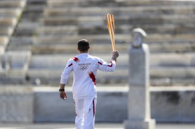 Atina, Yunanistan - 19 Mart 2020: Tokyo 2020 Yaz Olimpiyatları için Olimpiyat Alev devir töreni. Yunan Olimpiyat madalyası sahibi E. Petrounias, Panathenaic Stadyumu 'nda Tokyo Olimpiyat Alevi' ni düzenledi.