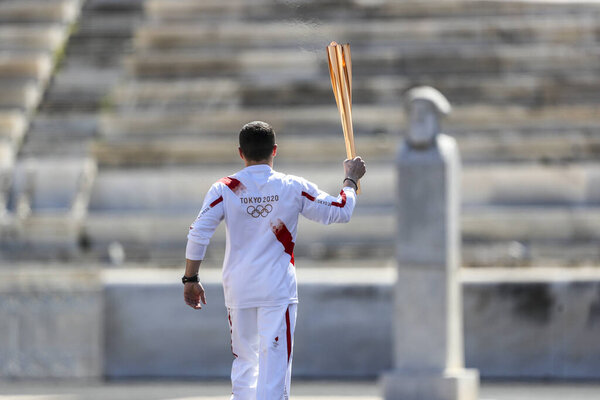 Athens, Greece - March 19, 2020: Olympic Flame handover ceremony for the Tokyo 2020 Summer Olympic Games. Greek Olympic medalist  E. Petrounias holds the Tokyo Olympic Flame at the Panathenaic stadium