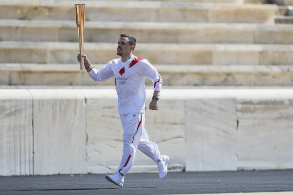 Athens, Greece - March 19, 2020: Olympic Flame handover ceremony for the Tokyo 2020 Summer Olympic Games. Greek Olympic medalist  E. Petrounias holds the Tokyo Olympic Flame at the Panathenaic stadium