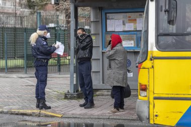 Selanik, Yunanistan - 23 Mart 2020: Bir polis memuru, COVID-19 adlı romanın yayılmasını kontrol etmeye çalışan bir vatandaşın belgelerini kontrol ediyor..