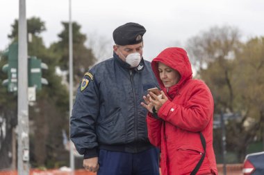 Selanik, Yunanistan - 23 Mart 2020: Bir polis memuru, COVID-19 adlı romanın yayılmasını kontrol etmeye çalışan bir vatandaşın belgelerini kontrol ediyor..