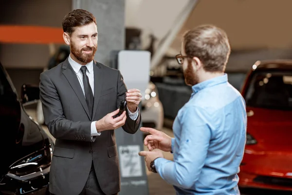 Cliente con un venditore presso lo showroom con auto elettriche — Foto Stock