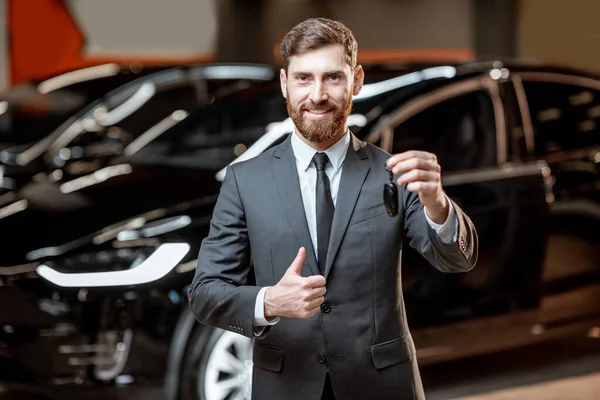 Verkäufer mit Schlüssel im Autohaus — Stockfoto