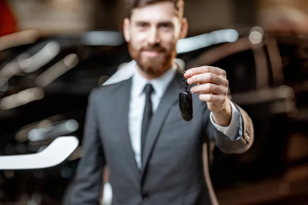 Salesman with key at the car dealership — Stock Photo, Image