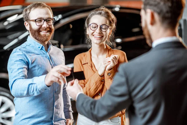 Couple with a seller at the car dealership — Stock Photo, Image
