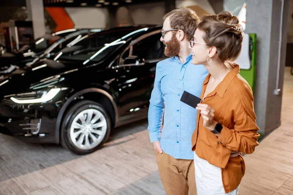 Pareja comprando coche eléctrico en el concesionario — Foto de Stock