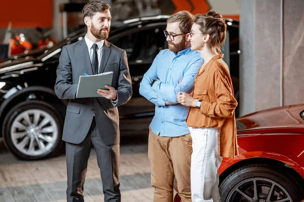 Coppia con responsabile vendite nella concessionaria auto — Foto Stock