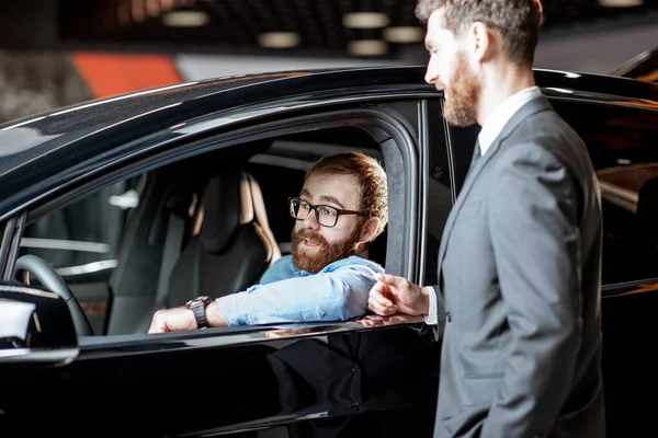 Gerente de ventas con un cliente mirando el interior del vehículo — Foto de Stock