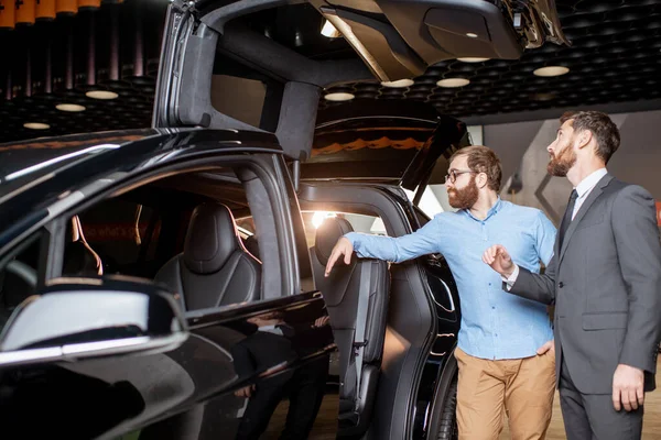 Cliente con un responsabile commerciale che ispeziona l'auto moderna nello showroom — Foto Stock