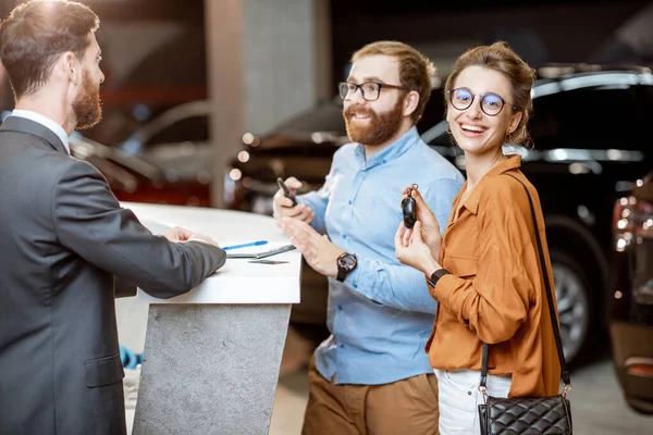 Responsabile vendite con una giovane coppia che acquista una macchina nuova — Foto Stock