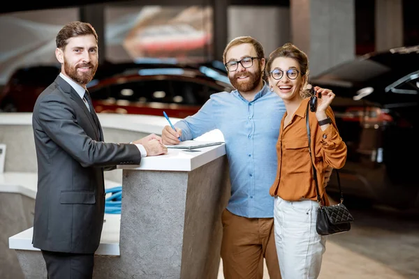 带着一对年轻夫妇买新车的销售经理 — 图库照片