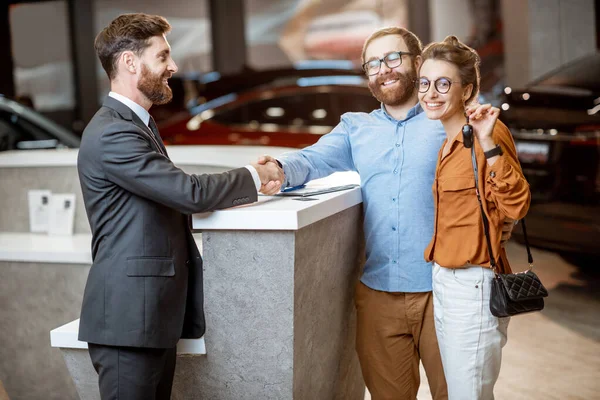 Responsabile vendite con una giovane coppia che acquista una macchina nuova — Foto Stock