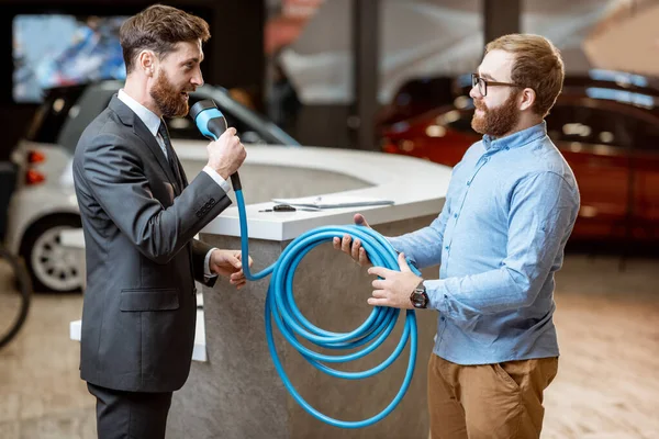 Vendedor dando cable para la carga del coche eléctrico a un cliente — Foto de Stock