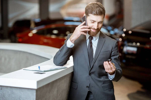 Businessman with car key in the showroom — Stock Photo, Image