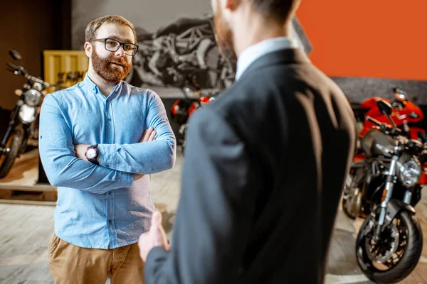 Sales consultant with a client in the showroom with motorcycles — Stock Photo, Image