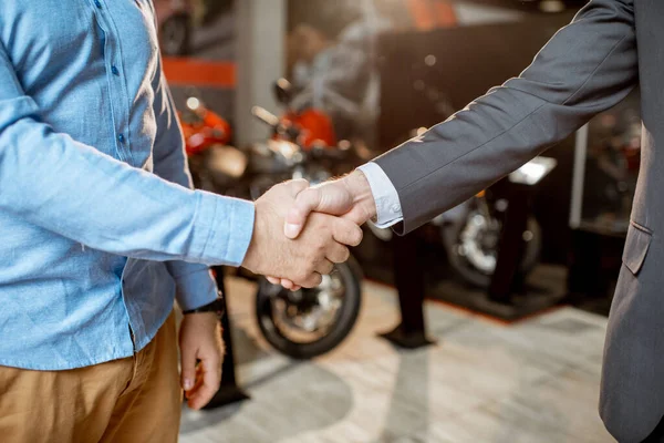 Apretón de manos en el showroom con motocicletas — Foto de Stock